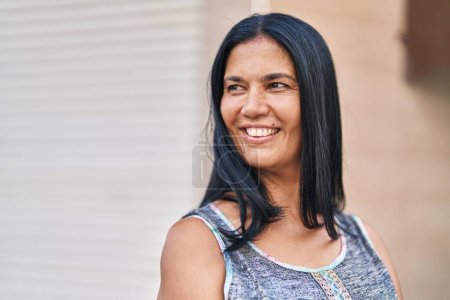 Foto de Middle age hispanic woman smiling confident looking to the side at street - Imagen libre de derechos