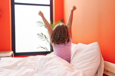 Foto de Adorable chica hispana despertando estirando los brazos en el dormitorio - Imagen libre de derechos