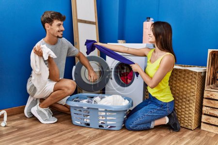 Téléchargez les photos : Man and woman couple fighting and washing clothes at laundry room - en image libre de droit