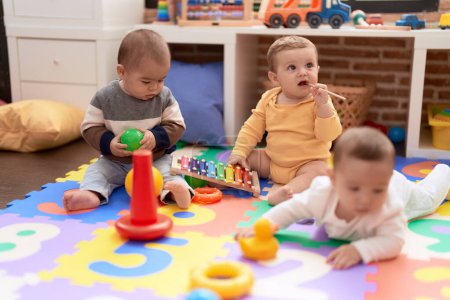 Photo for Group of toddlers playing with toys sitting on floor at kindergarten - Royalty Free Image