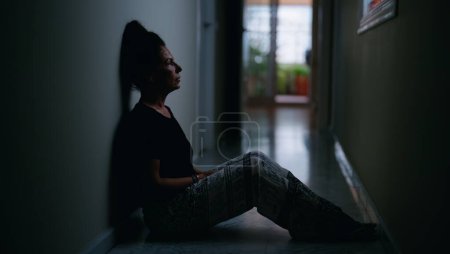 Photo for Middle age hispanic woman suffering for domestic violence with bruise on eyes sitting on floor at home - Royalty Free Image