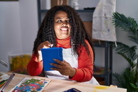 Téléchargez les photos : Artiste afro-américaine utilisant un smartphone dessin sur ordinateur portable au studio d'art - en image libre de droit