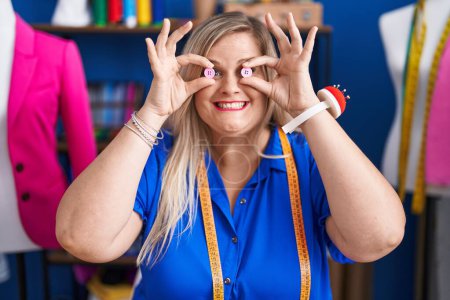 Téléchargez les photos : Young woman tailor smiling confident holding buttons over eyes at sewing studio - en image libre de droit