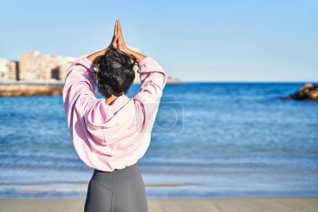 Photo for Young woman training yoga exercise standing at seaside - Royalty Free Image