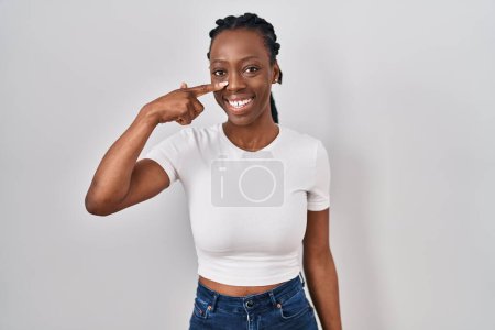 Téléchargez les photos : Beautiful black woman standing over isolated background pointing with hand finger to face and nose, smiling cheerful. beauty concept - en image libre de droit