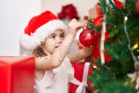 Foto de Adorable chica caucásica decorando árbol de Navidad en casa - Imagen libre de derechos