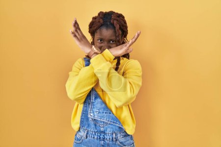 Foto de Mujer africana de pie sobre fondo amarillo rechazo expresión cruzando brazos haciendo signo negativo, cara enojada - Imagen libre de derechos