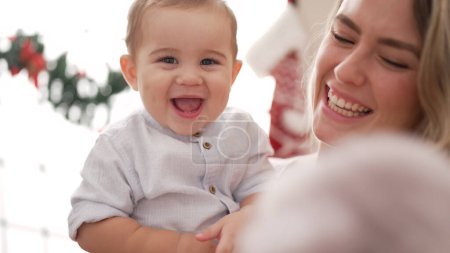Foto de Madre e hijo sonriendo confiados de pie por la decoración de Navidad en casa - Imagen libre de derechos