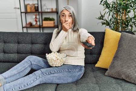 Foto de Mujer de pelo gris de mediana edad viendo películas en casa - Imagen libre de derechos