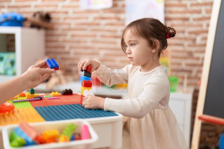 Téléchargez les photos : Adorable fille jouer avec des blocs de construction debout à la maternelle - en image libre de droit