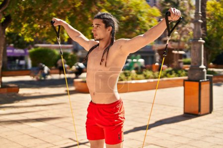 Téléchargez les photos : Young man training with elastic band at park - en image libre de droit