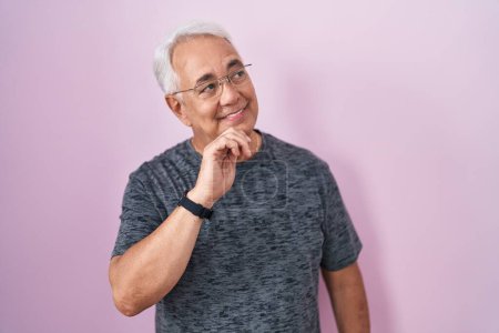 Photo for Middle age man with grey hair standing over pink background with hand on chin thinking about question, pensive expression. smiling and thoughtful face. doubt concept. - Royalty Free Image