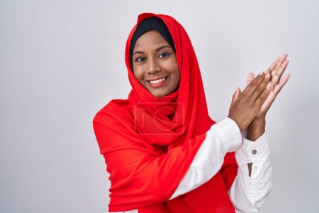 Photo for Young arab woman wearing traditional islamic hijab scarf clapping and applauding happy and joyful, smiling proud hands together - Royalty Free Image