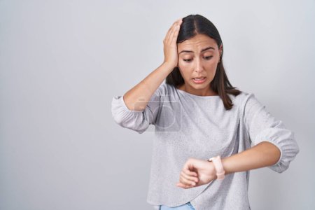Téléchargez les photos : Young hispanic woman standing over white background looking at the watch time worried, afraid of getting late - en image libre de droit