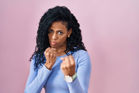 Téléchargez les photos : Middle age hispanic woman standing over pink background ready to fight with fist defense gesture, angry and upset face, afraid of problem - en image libre de droit