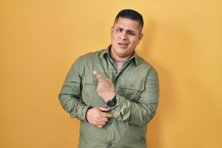 Téléchargez les photos : Jeune homme hispanique debout sur fond jaune pointant de côté inquiet et nerveux avec index, expression inquiète et surprise - en image libre de droit