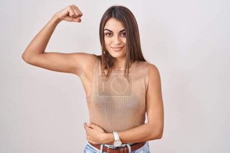 Photo for Young hispanic woman standing over white background strong person showing arm muscle, confident and proud of power - Royalty Free Image