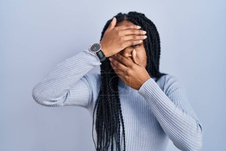 Photo for African american woman standing over blue background covering eyes and mouth with hands, surprised and shocked. hiding emotion - Royalty Free Image