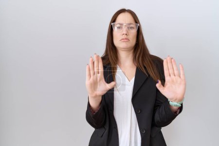 Photo for Beautiful brunette woman wearing business jacket and glasses moving away hands palms showing refusal and denial with afraid and disgusting expression. stop and forbidden. - Royalty Free Image