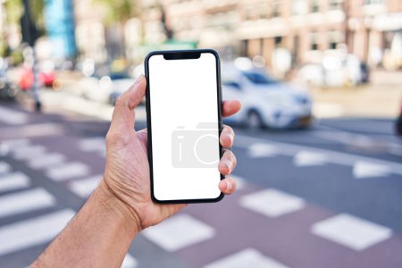 Téléchargez les photos : Homme tenant smartphone montrant écran blanc vierge à la rue - en image libre de droit