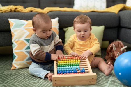 Photo for Two toddlers playing with abacus sitting on floor at home - Royalty Free Image