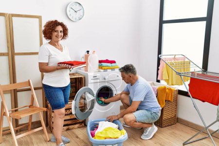Photo for Middle age man and woman couple smiling confident washing clothes at laundry - Royalty Free Image