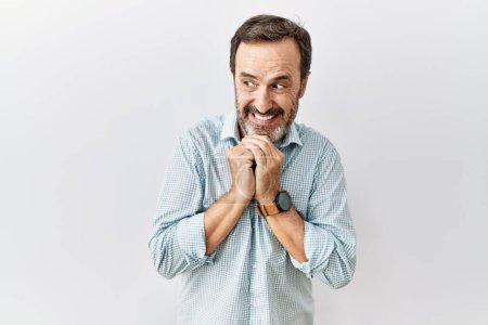 Téléchargez les photos : Moyen Age homme hispanique avec barbe debout sur fond isolé rire nerveux et excité avec les mains sur le menton regardant vers le côté - en image libre de droit
