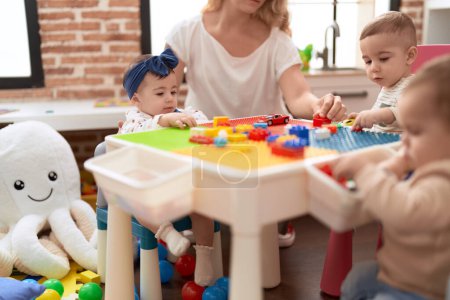 Photo for Group of toddlers playing with construction blocks sitting on table at kindergarten - Royalty Free Image