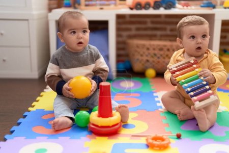 Foto de Dos niños pequeños jugando con pelota y xilófono en el jardín de infantes - Imagen libre de derechos