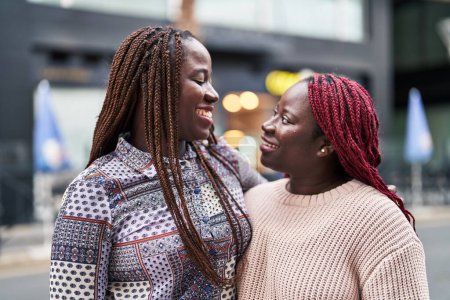Téléchargez les photos : Amis afro-américaines souriantes confiantes debout ensemble dans la rue - en image libre de droit