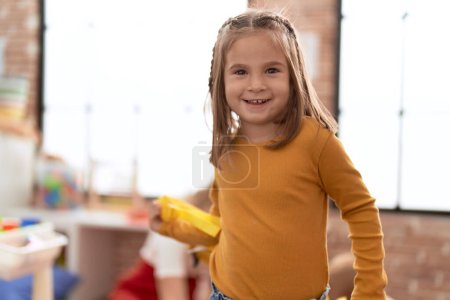 Foto de Adorable chica hispana sonriendo confiada de pie en el jardín de infantes - Imagen libre de derechos