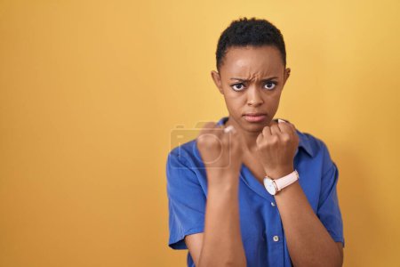 Téléchargez les photos : Femme afro-américaine debout sur fond jaune prêt à se battre avec geste de défense poing, visage en colère et bouleversé, peur du problème - en image libre de droit