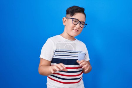Photo for Young hispanic kid standing over blue background disgusted expression, displeased and fearful doing disgust face because aversion reaction. with hands raised - Royalty Free Image