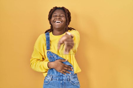 Téléchargez les photos : African woman standing over yellow background laughing at you, pointing finger to the camera with hand over body, shame expression - en image libre de droit