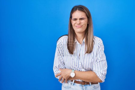 Photo for Hispanic young woman standing over blue background with hand on stomach because nausea, painful disease feeling unwell. ache concept. - Royalty Free Image