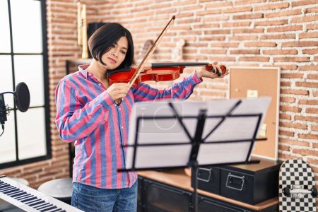 Photo for Young chinese woman musician playing violin at music studio - Royalty Free Image