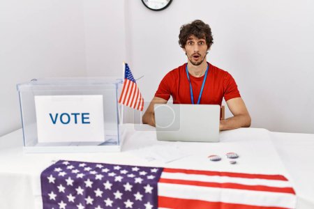 Photo for Young hispanic man at political election sitting by ballot afraid and shocked with surprise expression, fear and excited face. - Royalty Free Image