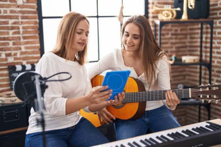 Two women musicians having classical guitar lesson at music studio