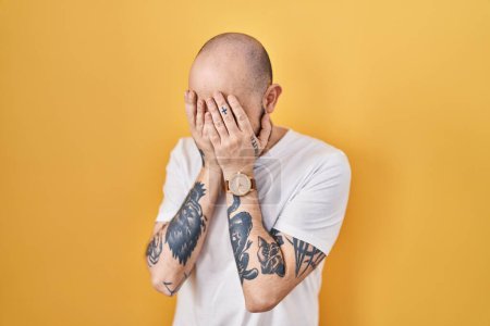 Photo for Young hispanic man with tattoos standing over yellow background with sad expression covering face with hands while crying. depression concept. - Royalty Free Image