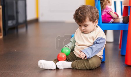 Photo for Adorable hispanic toddler playing with balls sitting on floor at kindergarten - Royalty Free Image