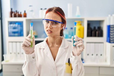 Photo for Young caucasian woman working at scientist laboratory holding samples clueless and confused expression. doubt concept. - Royalty Free Image