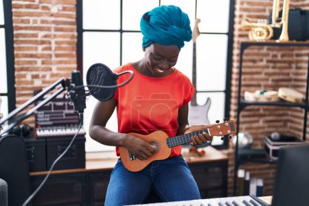 Photo for Young african american woman musician playing ukelele at music - Royalty Free Image