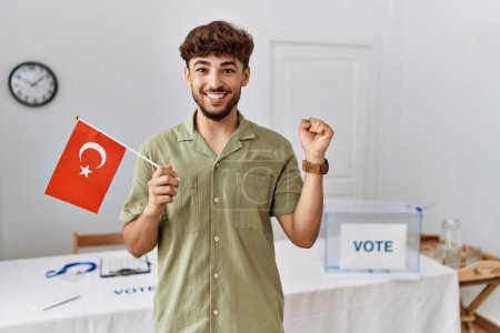 Téléchargez les photos : Jeune homme arabe à l'élection de la campagne politique tenant drapeau de dinde criant fier, célébrant la victoire et le succès très excité avec les bras levés - en image libre de droit