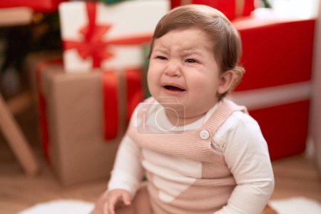 Foto de Adorable niño sentado en el suelo por regalo de Navidad llorando en casa - Imagen libre de derechos