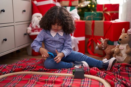 Téléchargez les photos : Afro-américain tout-petit jouer avec jouet de voiture assis sur le sol par arbre de Noël à la maison - en image libre de droit