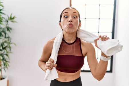 Photo for Young hispanic woman wearing sportswear and towel at sport center looking at the camera blowing a kiss being lovely and sexy. love expression. - Royalty Free Image