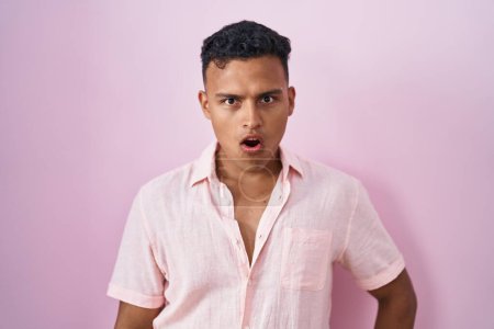 Photo for Young hispanic man standing over pink background in shock face, looking skeptical and sarcastic, surprised with open mouth - Royalty Free Image