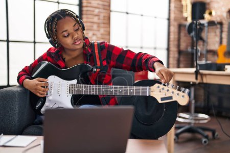 Foto de Afro-americana mujer músico teniendo en línea guitarra eléctrica lección en estudio de música - Imagen libre de derechos