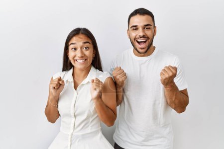Photo for Young interracial couple standing together in love over isolated background celebrating surprised and amazed for success with arms raised and open eyes. winner concept. - Royalty Free Image