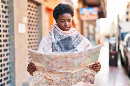 Téléchargez les photos : Femme afro-américaine souriante confiante tenant la carte de la ville à la rue - en image libre de droit